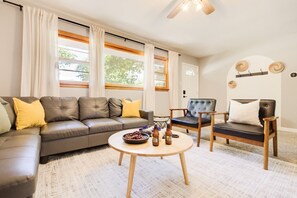 A living room with a sofa, two chairs, a coffee table, and a ceiling fan.