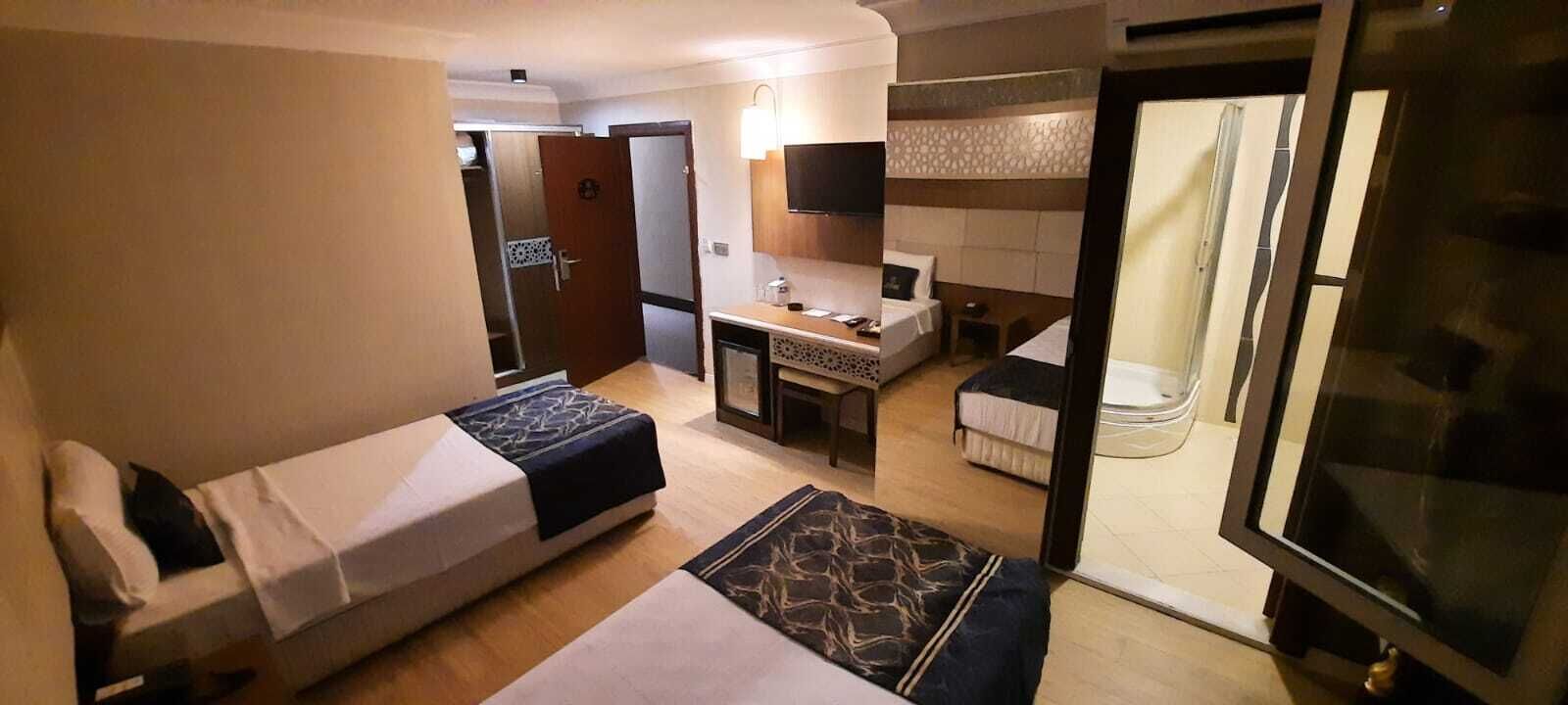 Habitación de hotel con cama, escritorio, una mesita, zona de ducha y televisor.