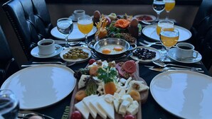 Una mesa de desayuno con platos de comida, vasos y vistas al mar.