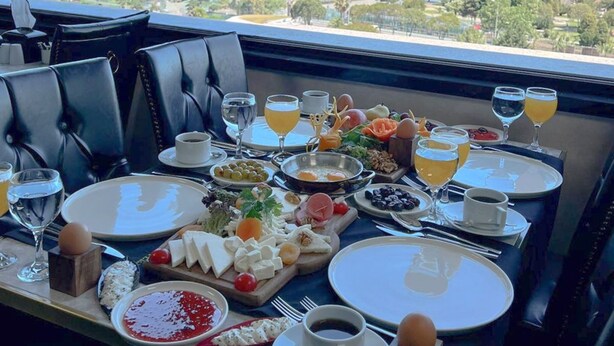 Una mesa de comedor dispuesta con alimentos para el desayuno y una vista panorámica del mar.