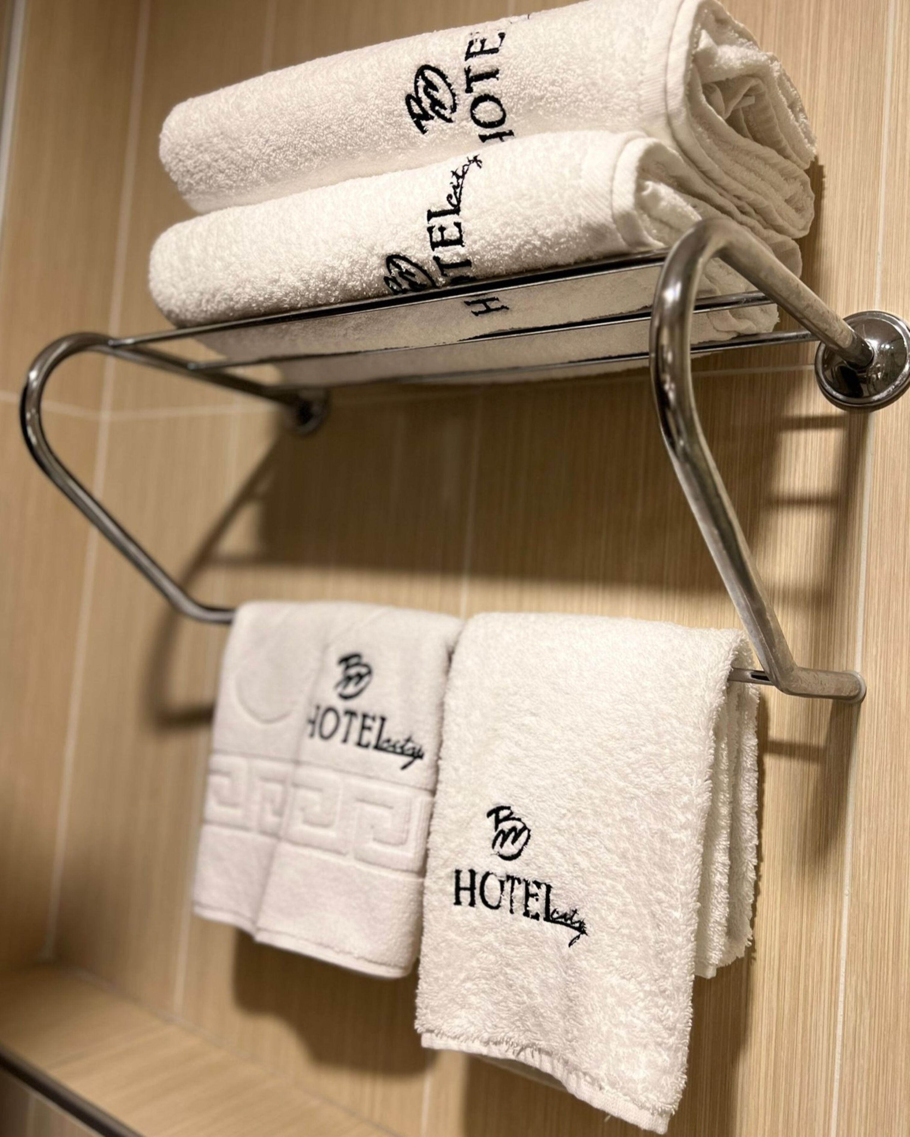 A bathroom with a towel rack holding two folded towels and a single towel hanging.