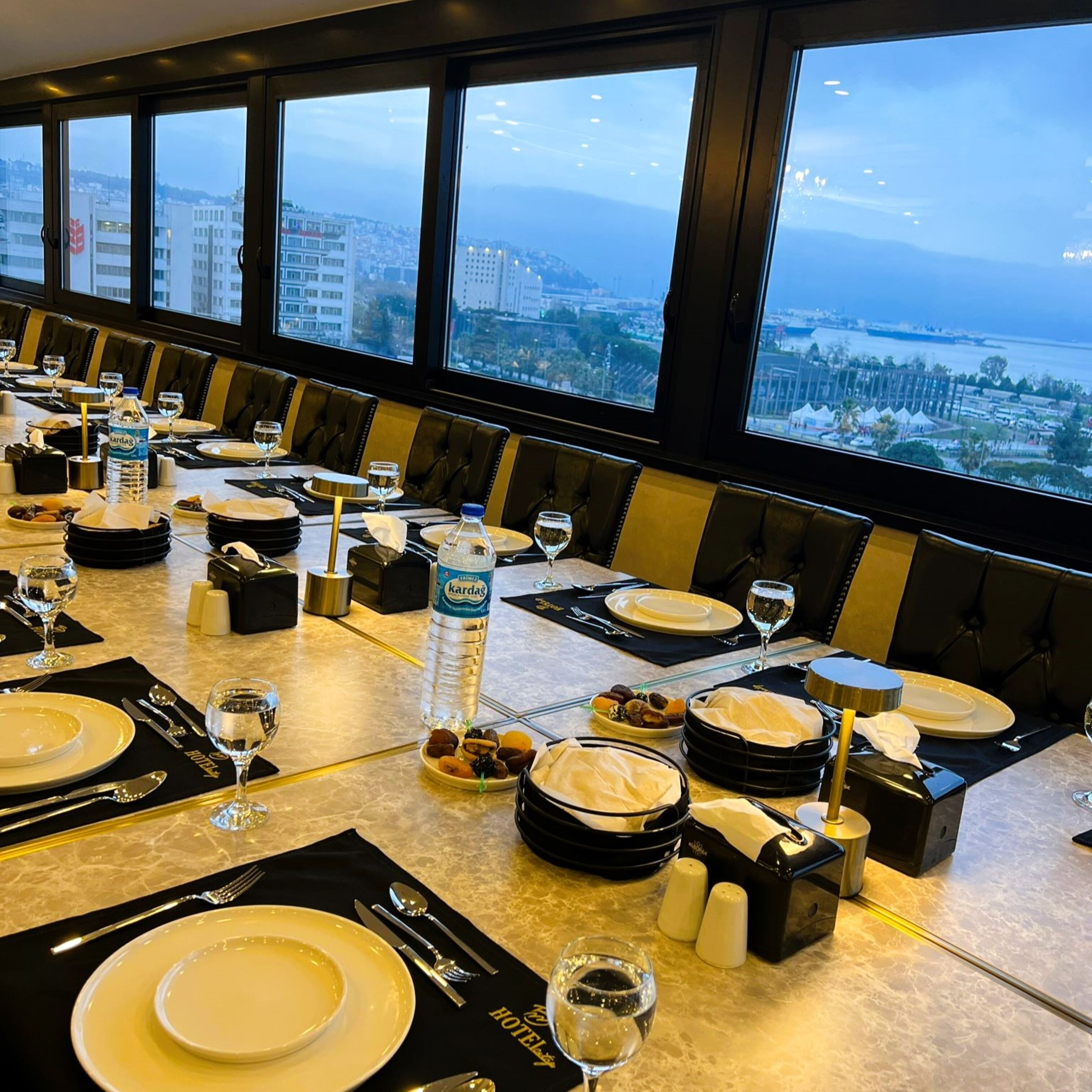 Ein Restaurant mit gedeckten Tischen und Blick auf Stadt und Meer.