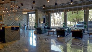 Zona de recepción de un hotel con suelo de mármol, sofás de cuero e iluminación colgante.