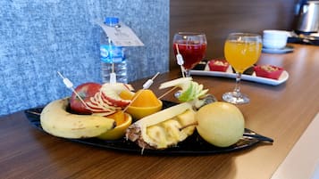 Une assiette de fruits variés et deux verres de jus de fruits sont posés sur une table.