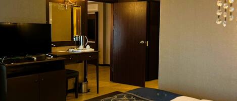 A hotel room with a bed, a desk, a television, and an air conditioning unit.