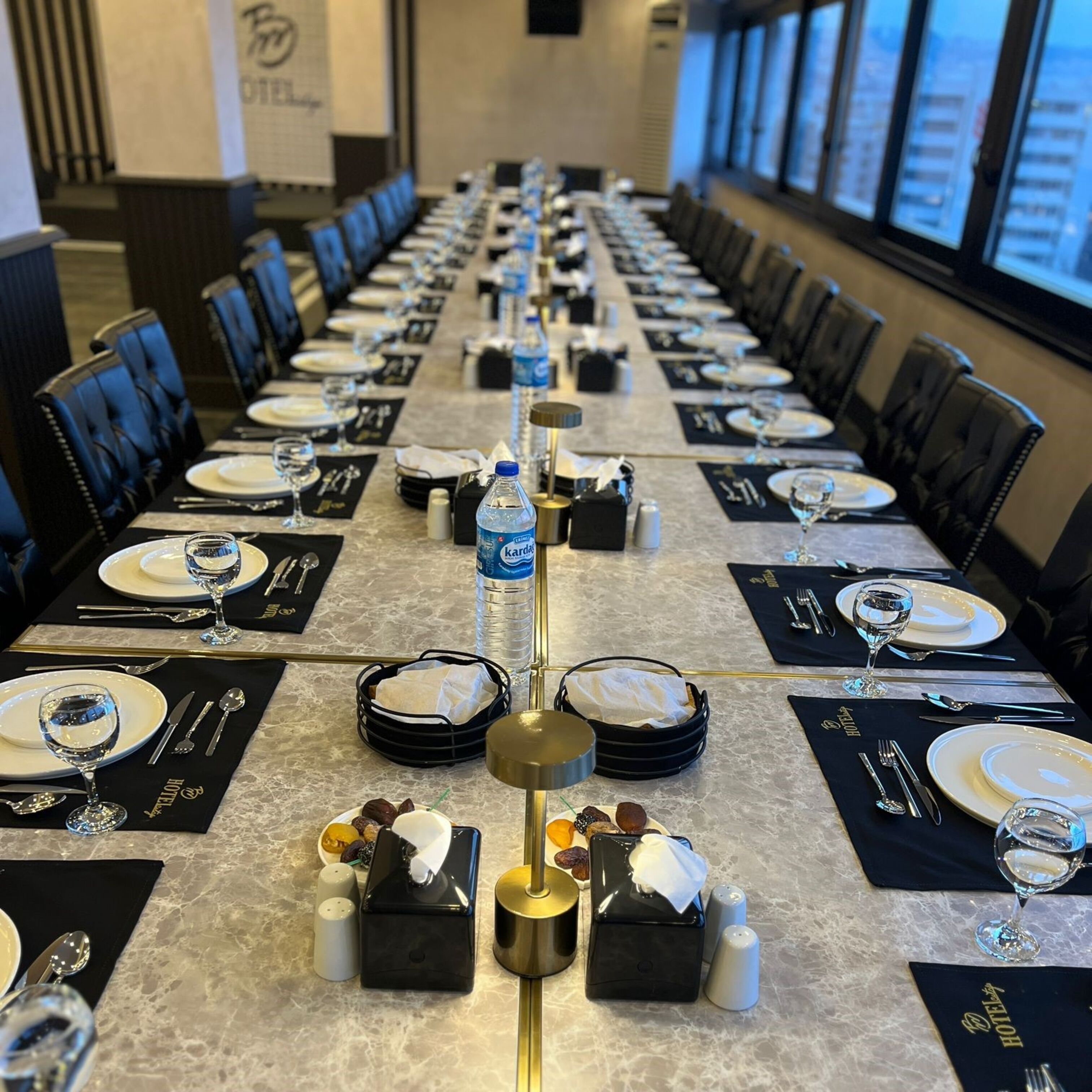 A long conference table set for a meeting with water bottles, salt and pepper shakers, and a tissue dispenser.