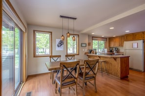 Enjoy meals in the kitchen with an island and dining area featuring a wooden table and pendant lights.