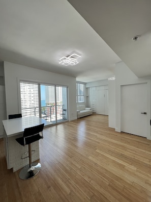 A spacious living area with a dining table, a bar stool, and a sofa.