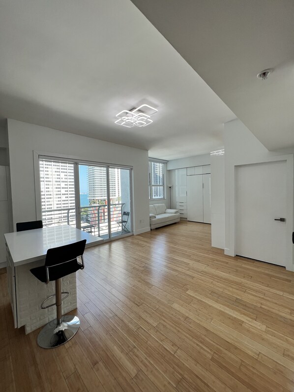 A spacious living area with a dining table, a bar stool, and a sofa.