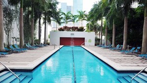 A swimming pool with blue water, surrounded by palm trees and lounge chairs. - Fully Equipped Modern Loft in the Heart of Miami (Miami)