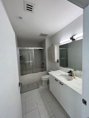 A bathroom with a shower, toilet, and sink.