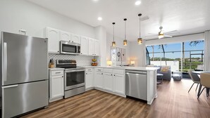 Una cocina moderna con armarios blancos, electrodomésticos de acero inoxidable y suelo de madera.