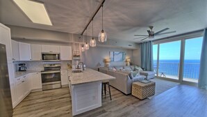 Una cucina moderna con mobili bianchi, un'isola centrale e illuminazione a sospensione.