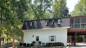 A house with a stone pathway leading to the front door, surrounded by greenery and trees.