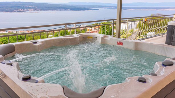 A hot tub with a view of a body of water and distant landscape. - Holiday apartment with terrace and air conditioning (Crikvenica)