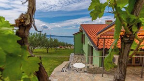 A house with a tiled roof, a stone patio, and a view of the sea.