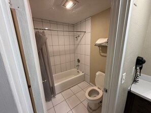 A bathroom with a bathtub, toilet, and a shower area.