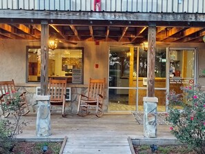 A wooden deck with outdoor seating, a private parking sign, and a glass door entrance.