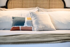 Una cama con varias almohadas, cabecera y colcha.