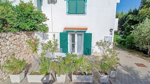 A white building with green shutters, a stone wall, and potted plants in front. - 100 metres to the beach (Baska)