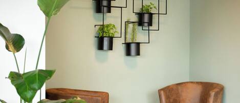 A room with a brown leather chair, a small round table, and a wall-mounted plant arrangement.