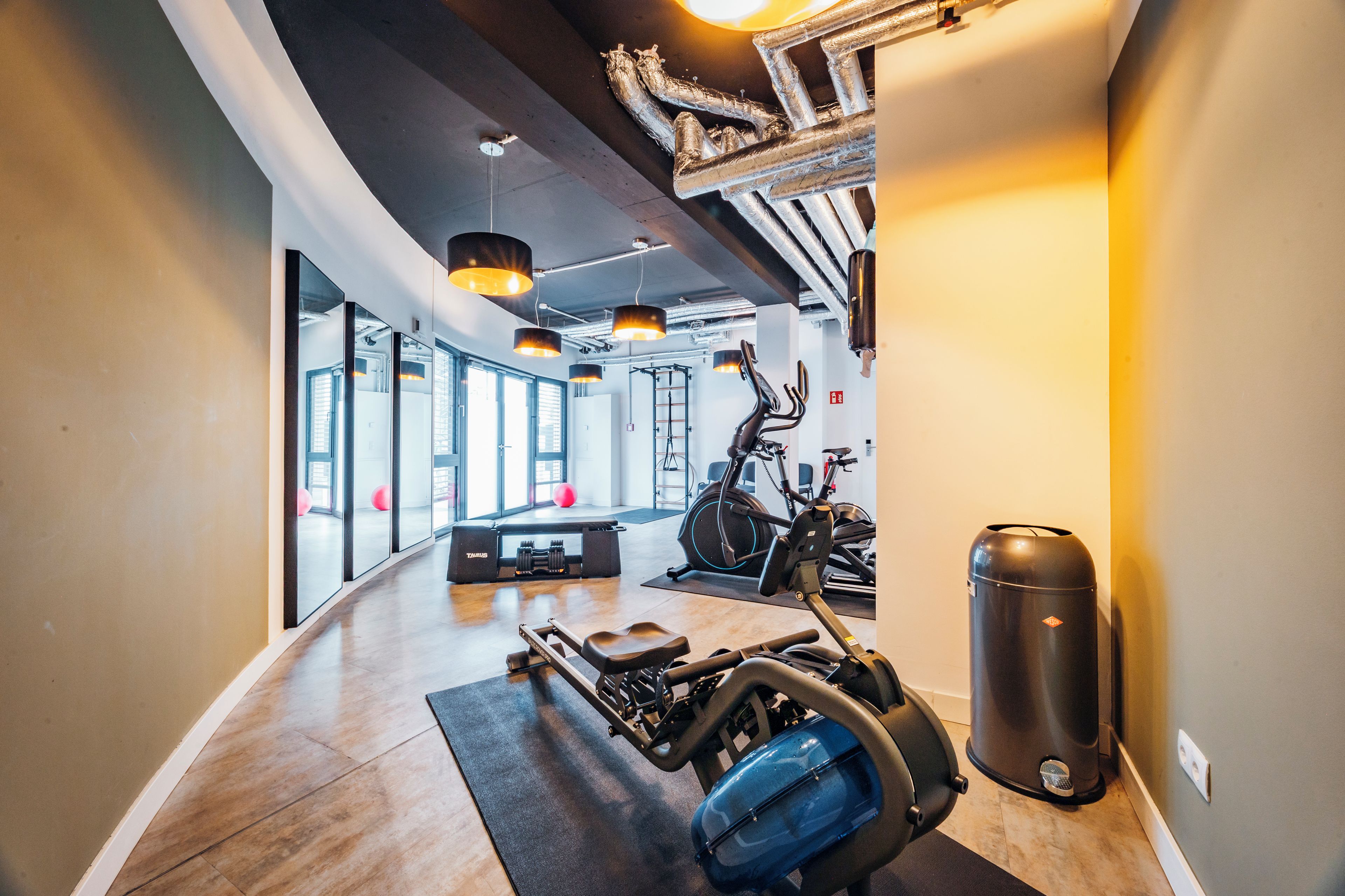 Ein Fitnessstudio mit Trainingsgeräten, einem Rudergerät und einem Fahrradergometer.