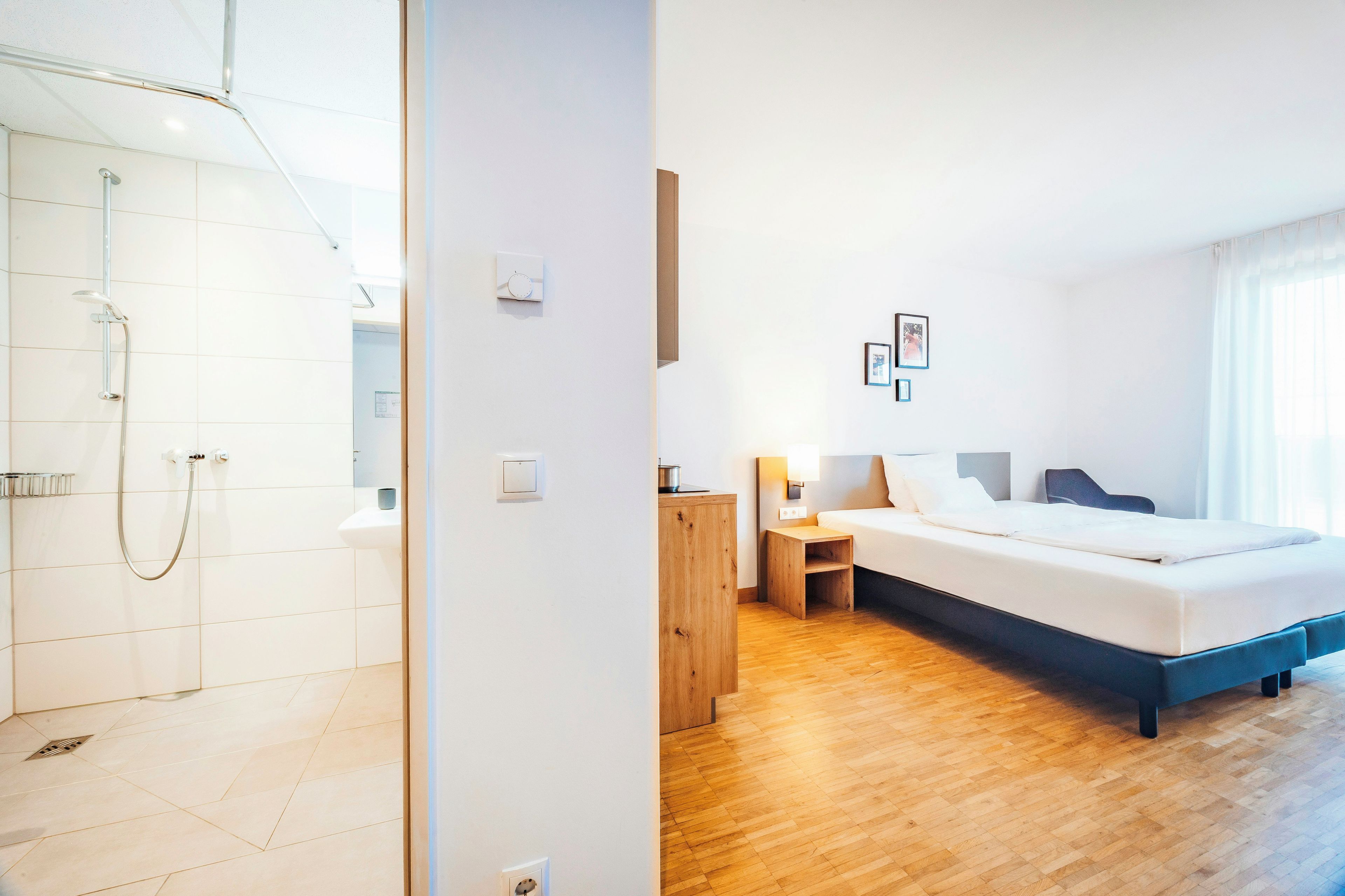 Een hotelkamer met een douche, een bed, een nachtkastje en een bijzettafeltje.