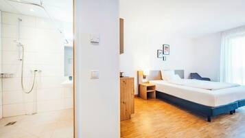 Een hotelkamer met een douche, een bed, een nachtkastje en een bijzettafeltje.