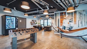 A modern indoor space with a foosball table, a vending machine, and a hammock.
