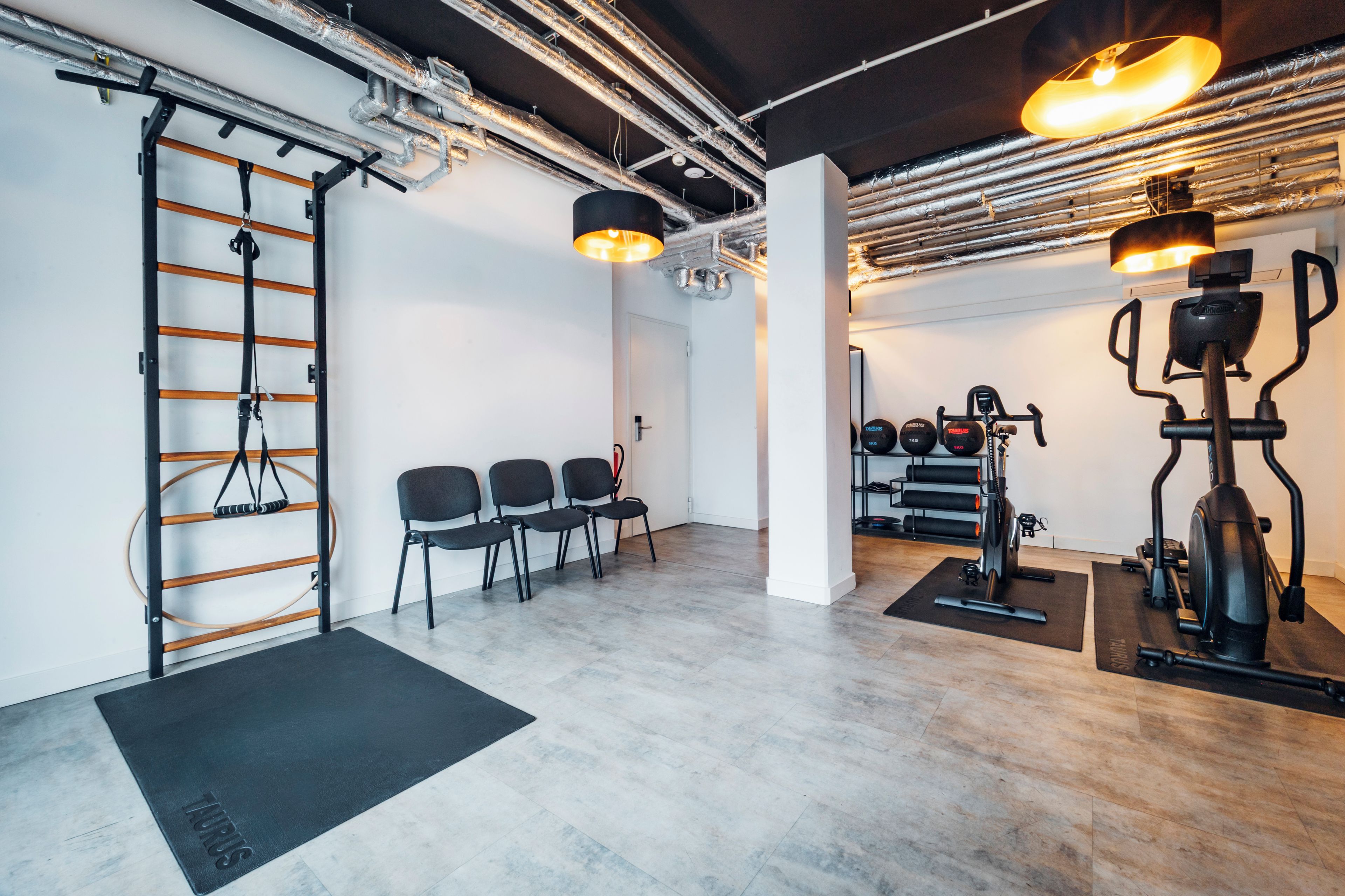 Een sportschool met trainingsapparatuur, een optrekstang en een wandrek.