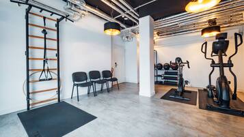 Een sportschool met trainingsapparatuur, een optrekstang en een wandrek.