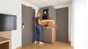 Cocina pequeña con microondas, pileta y encimera de madera.
