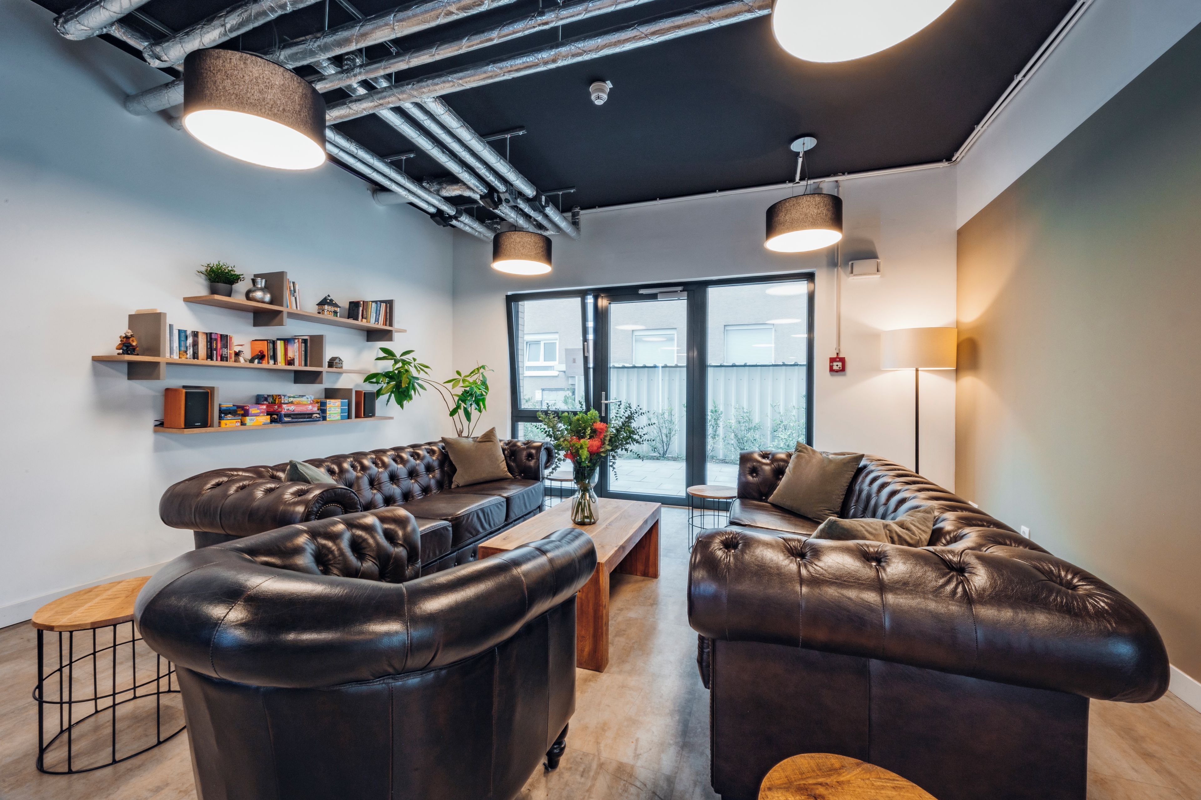 Ein modernes Interieur mit Ledersofas, einem Holztisch und einem Bücherregal mit verschiedenen Gegenständen.