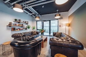 A modern interior with leather sofas, a wooden coffee table, and a bookshelf with various items. - Brera Serviced Apartments Stuttgart (Stuttgart)