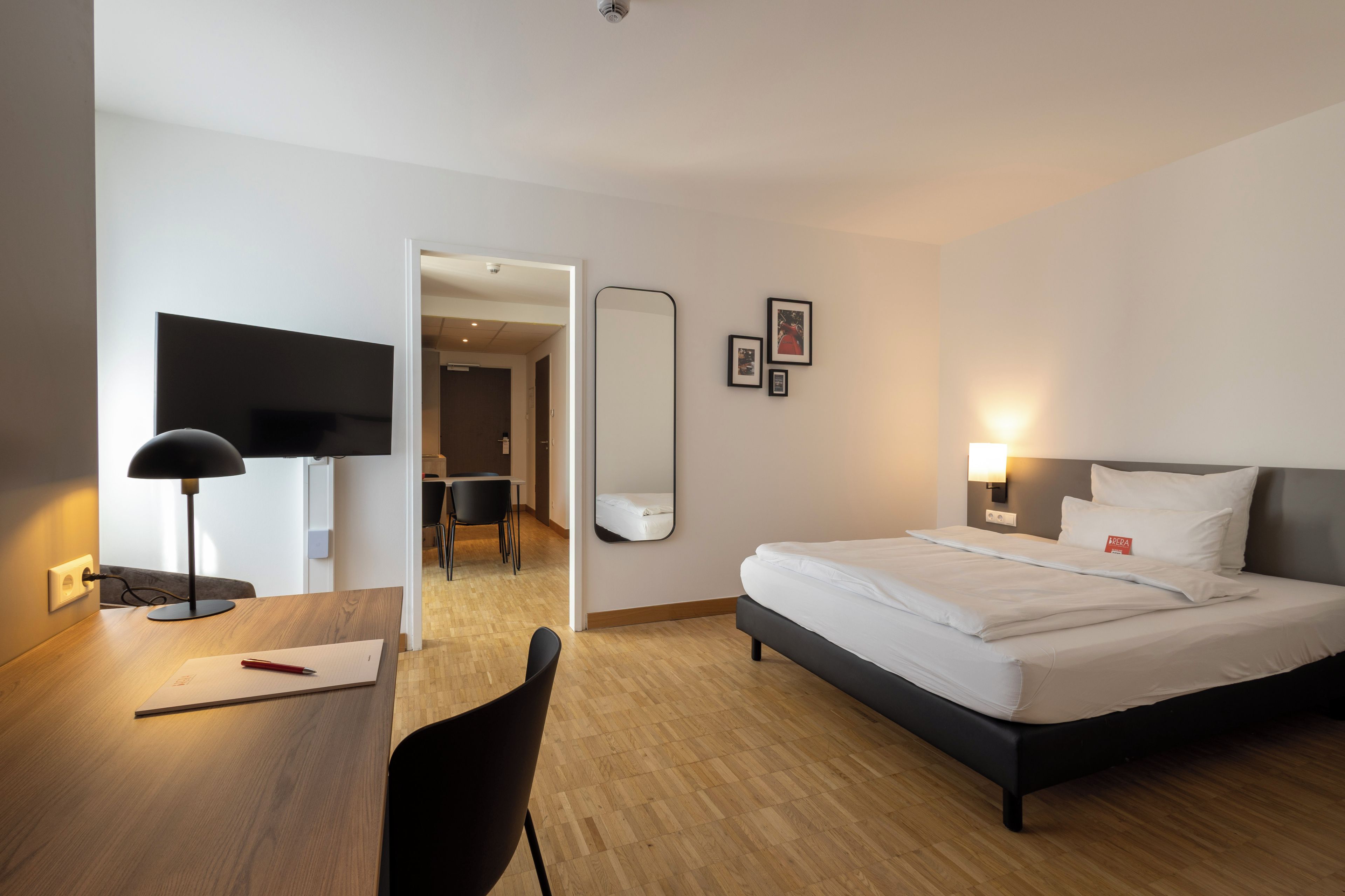 A hotel room with a bed, desk, chair, and a television.