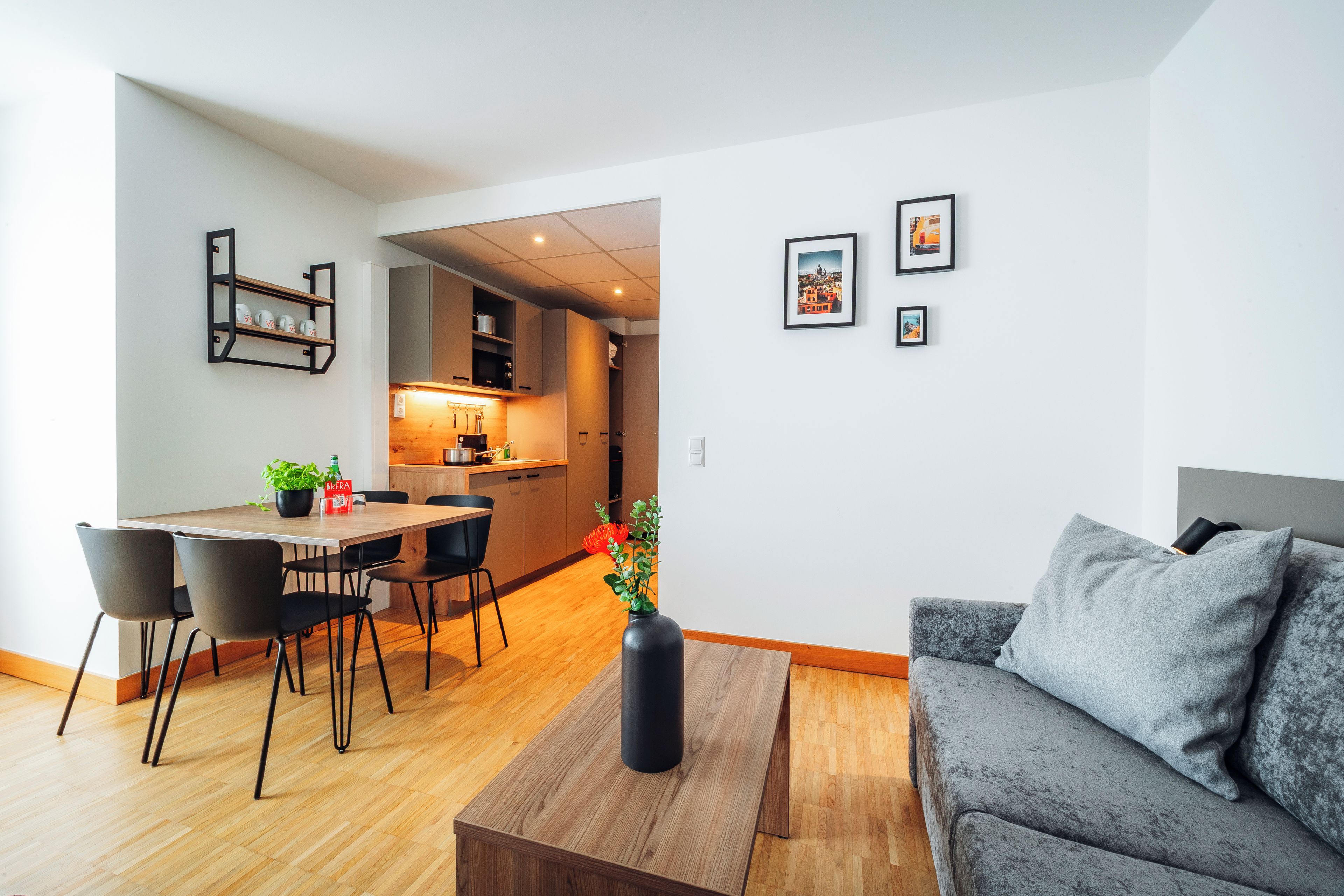 Ein modernes Wohnzimmer mit einem grauen Sofa, einem Holztisch und einem Essbereich mit einem Holztisch und Stühlen.