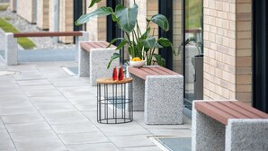 Un área de estar al aire libre con macetas de hormigón, una mesa de metal y bancos.