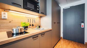 Una cocina moderna con armarios de madera, un lavamanos de acero inoxidable y un microondas.