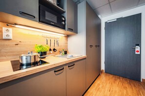 A modern kitchen with wooden cabinets, a stainless steel sink, and a microwave. - Brera Serviced Apartments Stuttgart (Stuttgart)