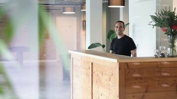 Un comptoir d’accueil avec un revêtement en bois, une plante en pot et un vase rempli de fleurs.