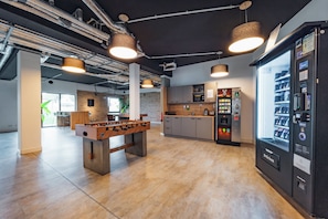 A modern indoor space with a foosball table, a coffee machine, and a vending machine. - Brera Serviced Apartments Stuttgart (Stuttgart)