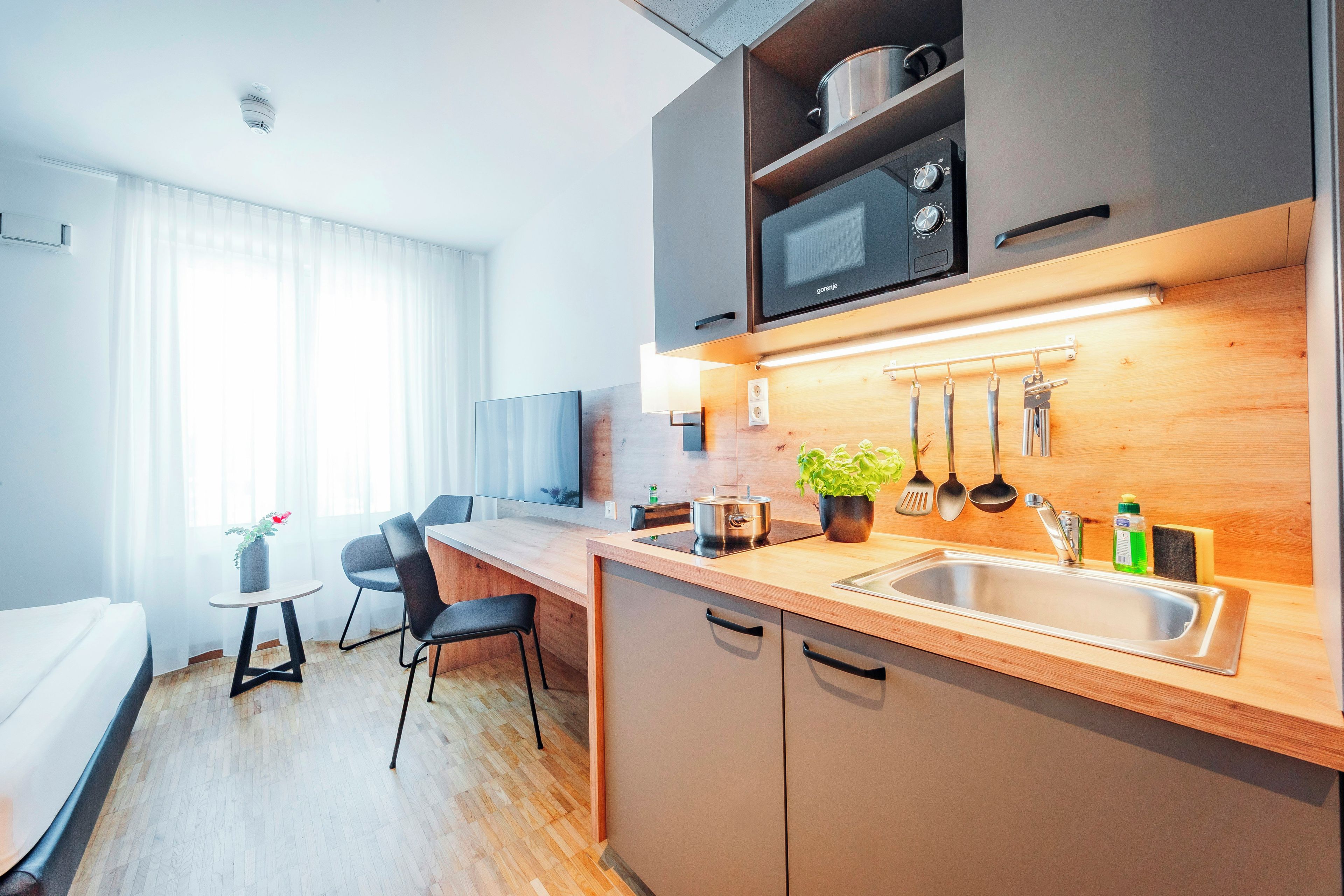 A modern kitchen with a wooden countertop, stainless steel sink, and overhead microwave.