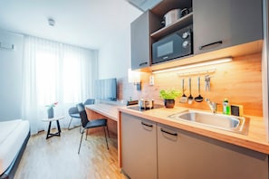 A modern kitchen with a wooden countertop, stainless steel sink, and overhead microwave. - Brera Serviced Apartments Stuttgart (Stuttgart)