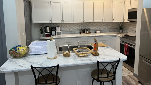 A kitchen with white cabinets, a marble countertop, and a stainless steel refrigerator. - Lovely 2 bedroom rental unit with free parking (Columbus)