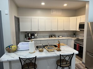 A kitchen with white cabinets, a marble countertop, and a stainless steel refrigerator. - Lovely 2 bedroom rental unit with free parking (Columbus)