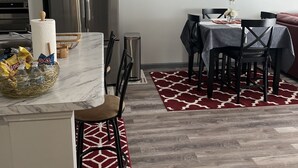 A modern kitchen with a stainless steel refrigerator, a marble countertop, and a dining area with a table and chairs. - Lovely 2 bedroom rental unit with free parking (Columbus)