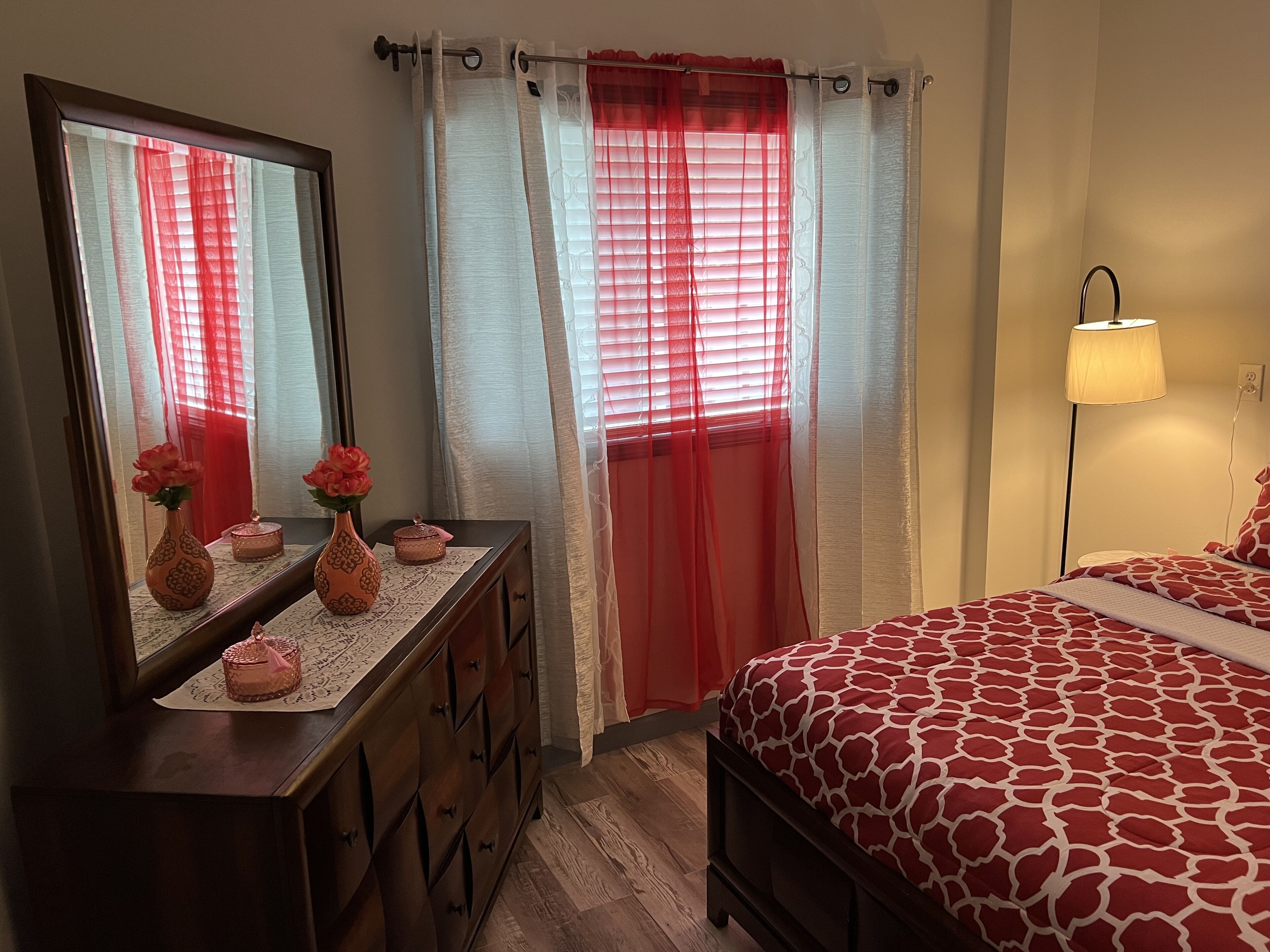 Um quarto com uma cama, penteadeira, espelho e mesa de cabeceira.