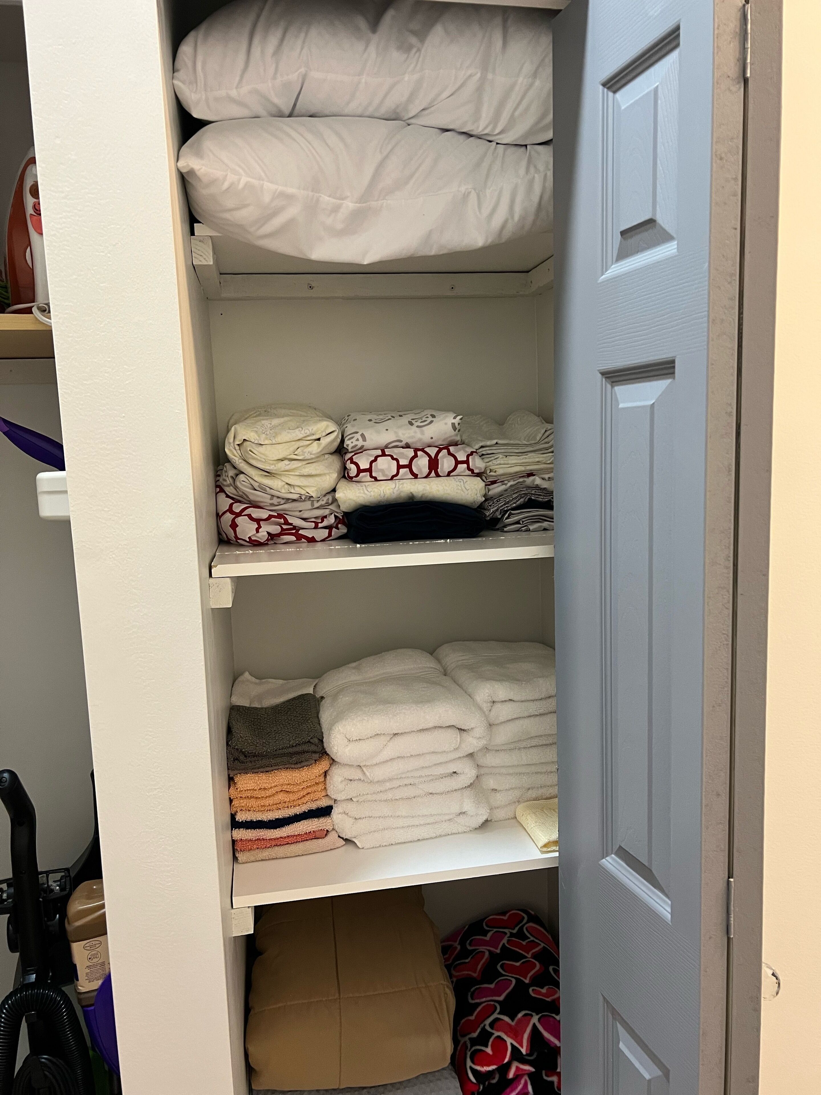 A closet with shelves holding folded towels and blankets.