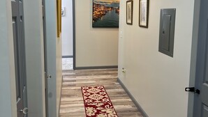 A hallway with a red carpet, a painting, and a door. - Lovely 2 bedroom rental unit with free parking (Columbus)