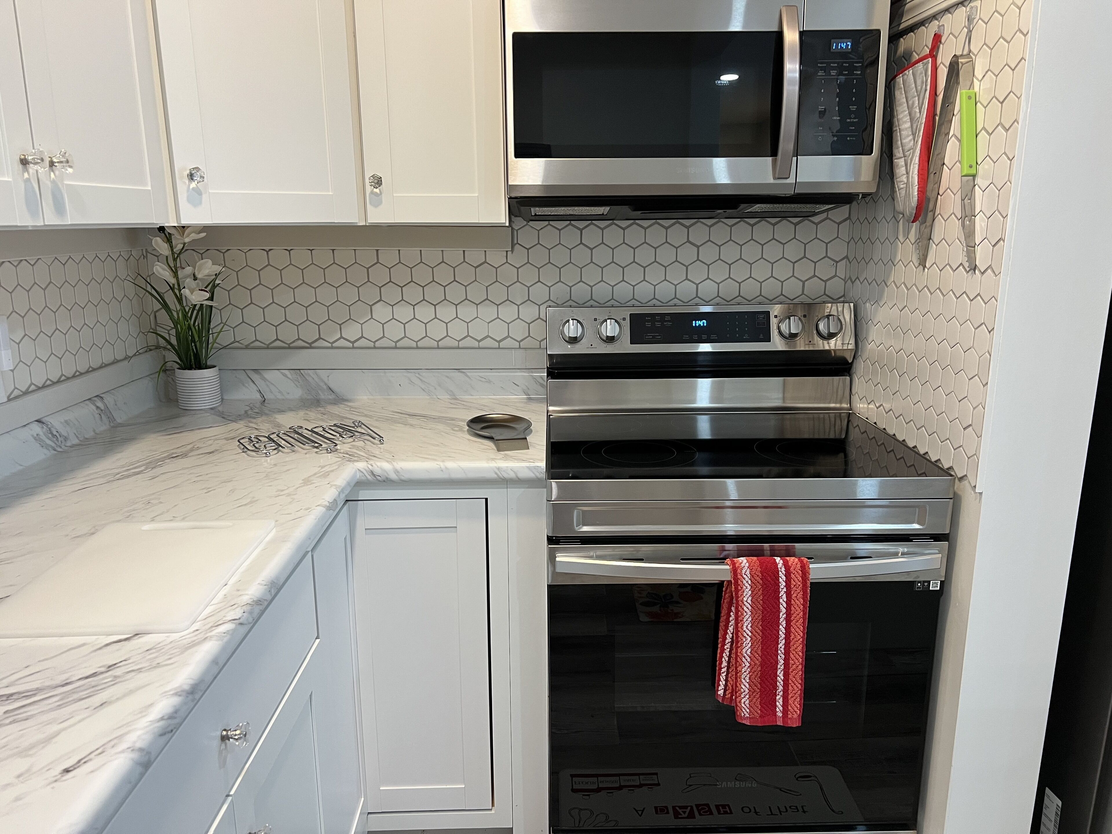 A kitchen with white cabinets, a microwave, and two ovens.